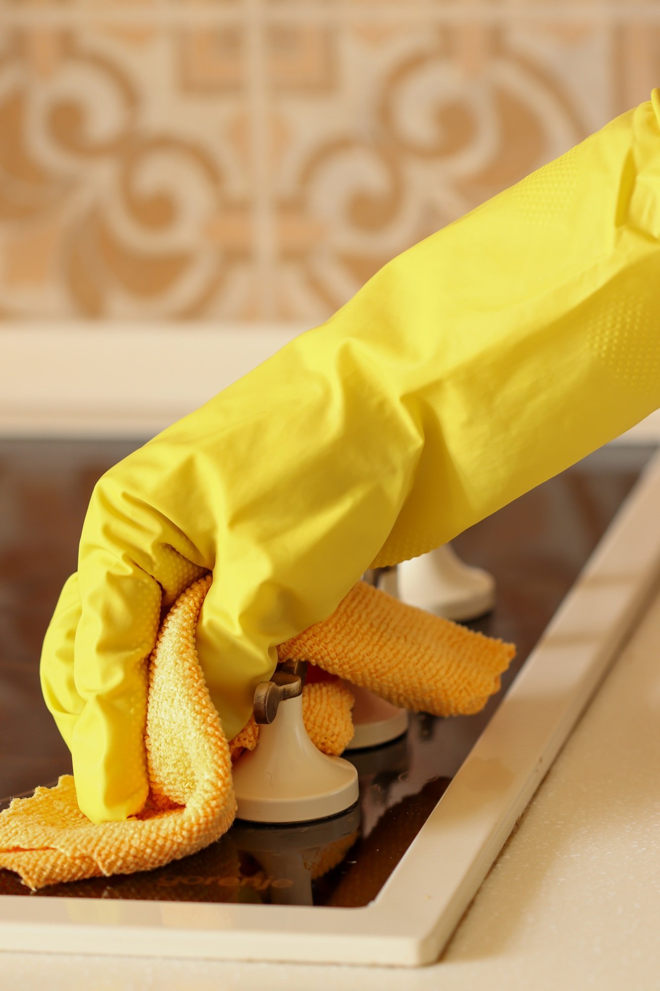 A woman washes the hob of an electric stove with detergent. cleaning the house