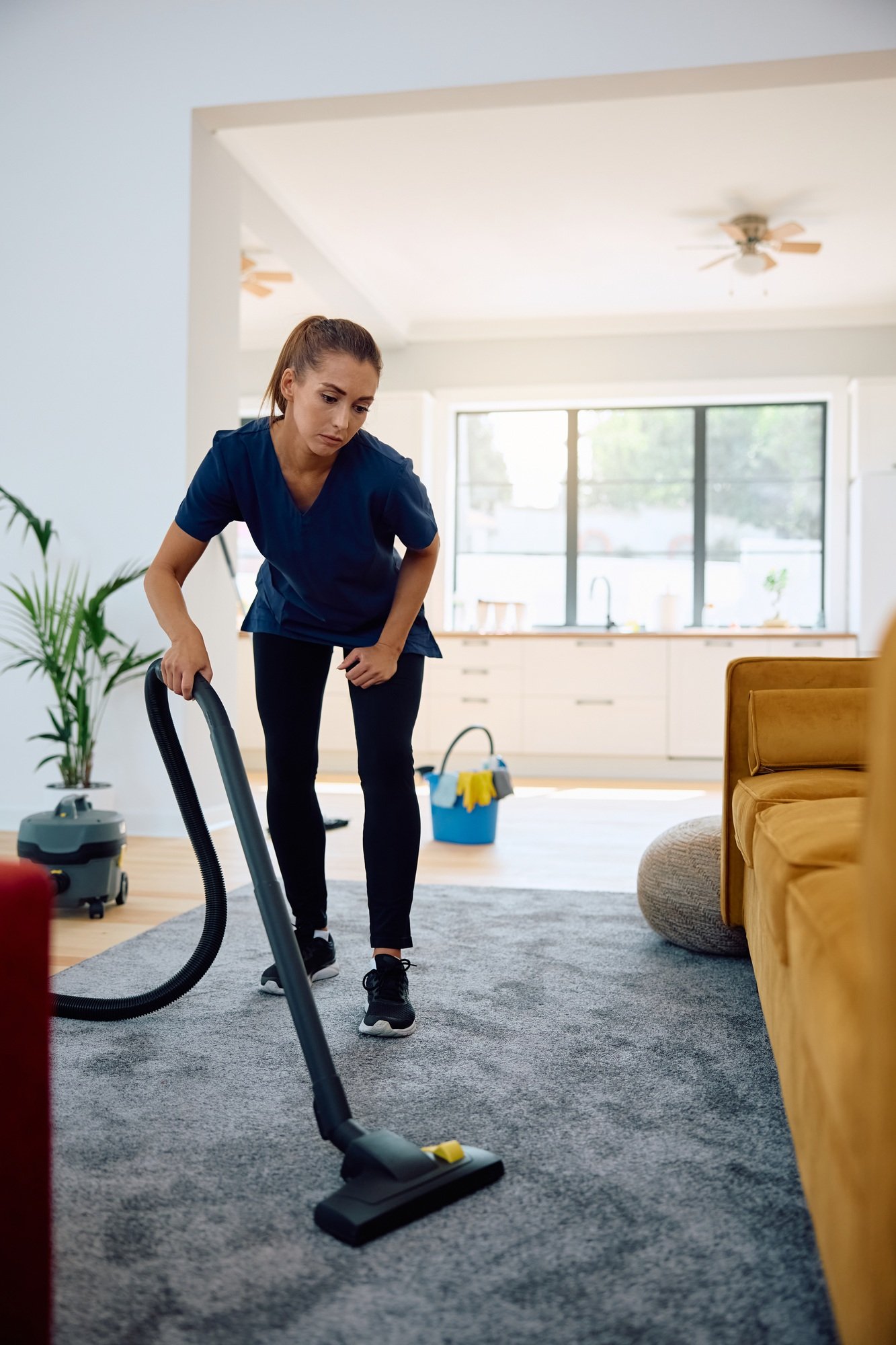 Young woman vacuuming while working professional cleaner.